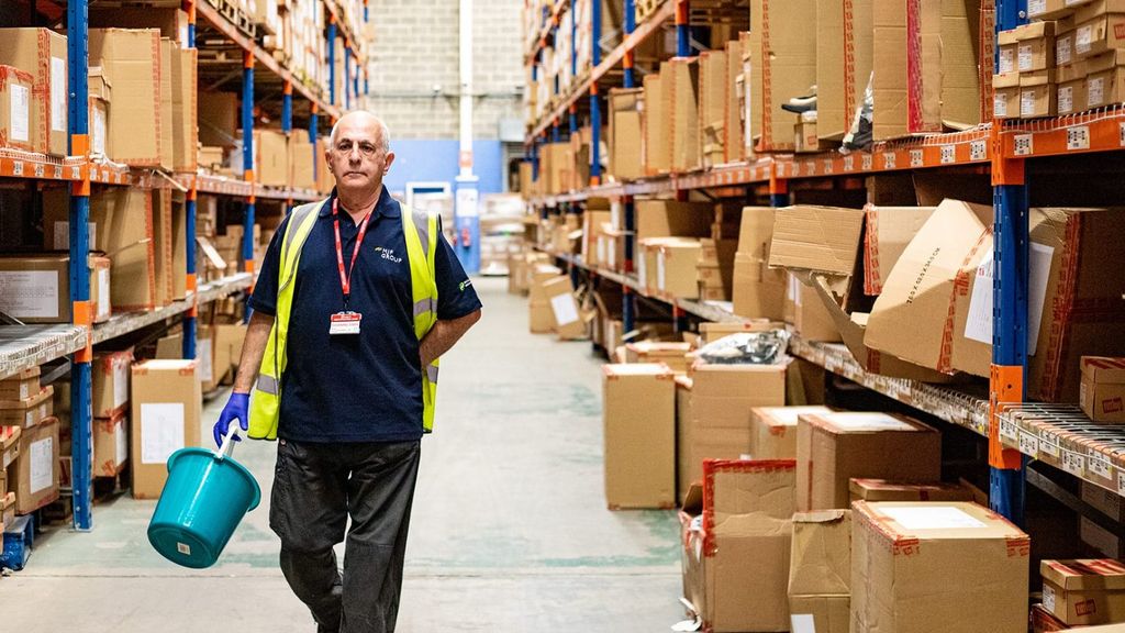 A man in a yellow high-visibility jacket inspecting a warehouse